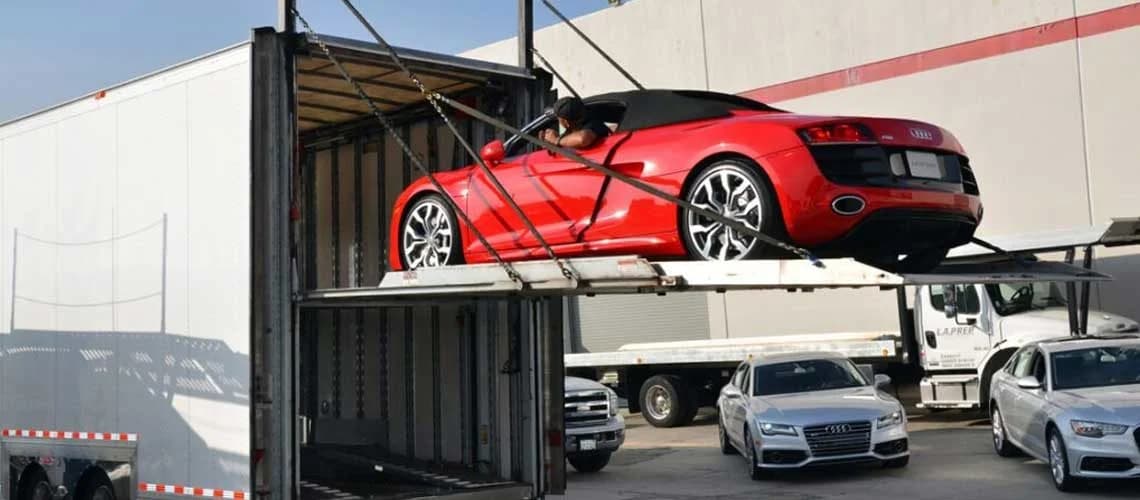Red Audi being loaded into a shipping container at an automotive yard