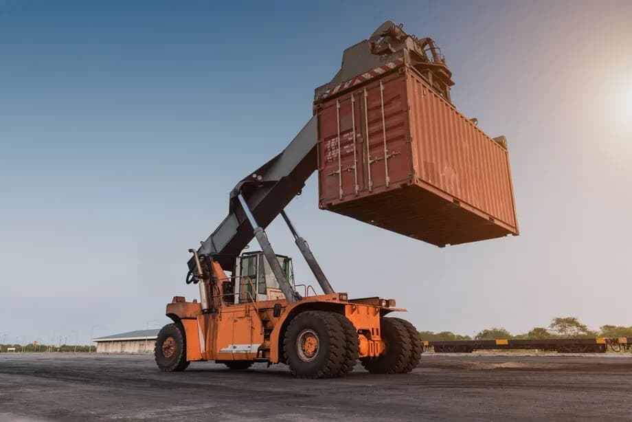 A shipping container being lifted by heavy equipment
