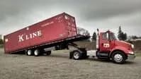 Tilt-bed trailer offloading a container.