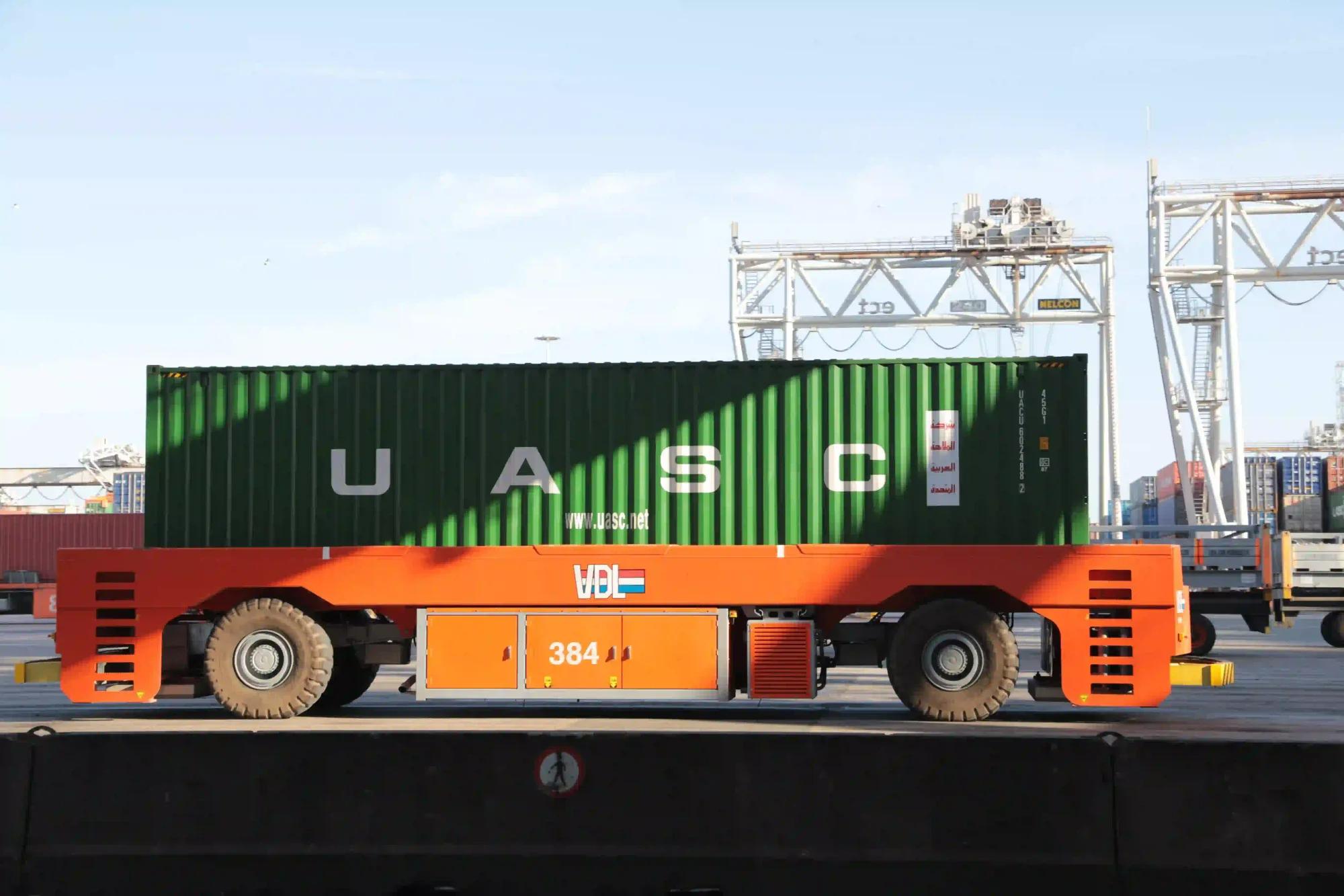 Green shipping container on a straddle carrier at a port terminal