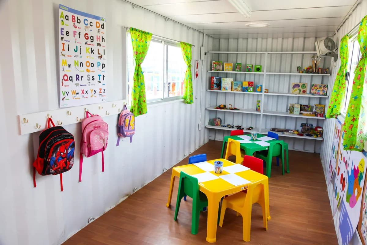 Bright shipping container classroom interior with alphabet posters and child-sized desks