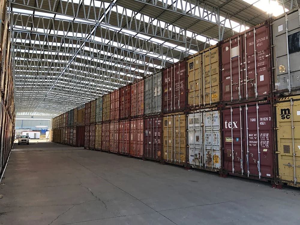 Stacked shipping containers inside a warehouse used as long-term storage